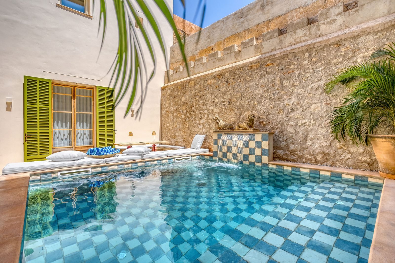 Piscina de gresite azul junto al muro de piedra del casal