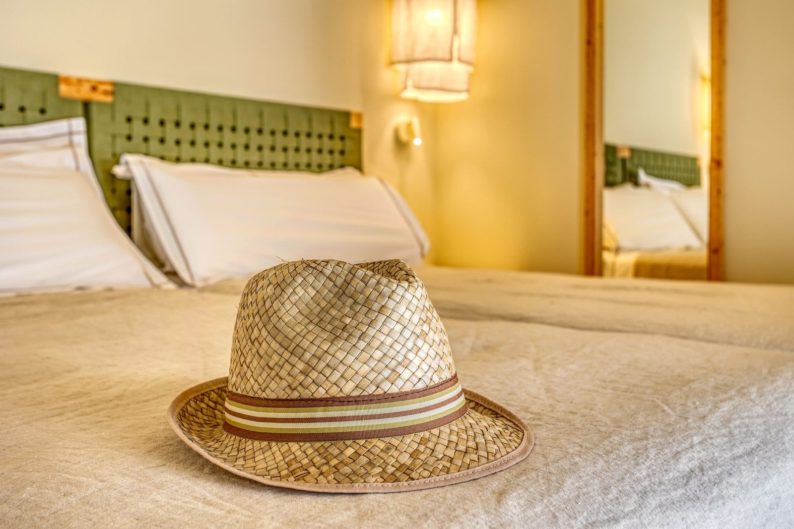 Sombrero de paja sobre la cama, con cabecero de mimbre tejido a mano