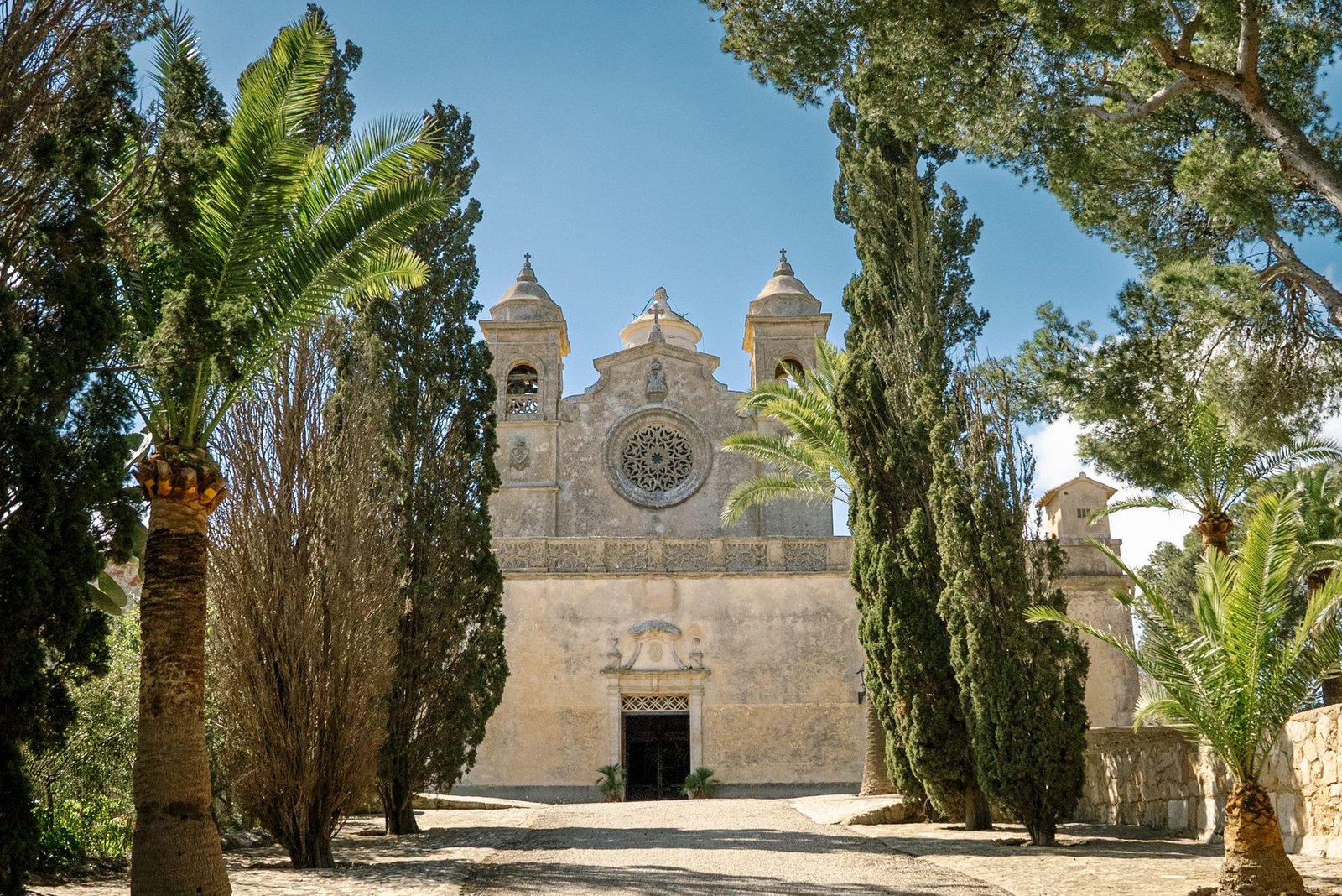 Fachada del Santuari de Bonany entre cipreses y palmeras